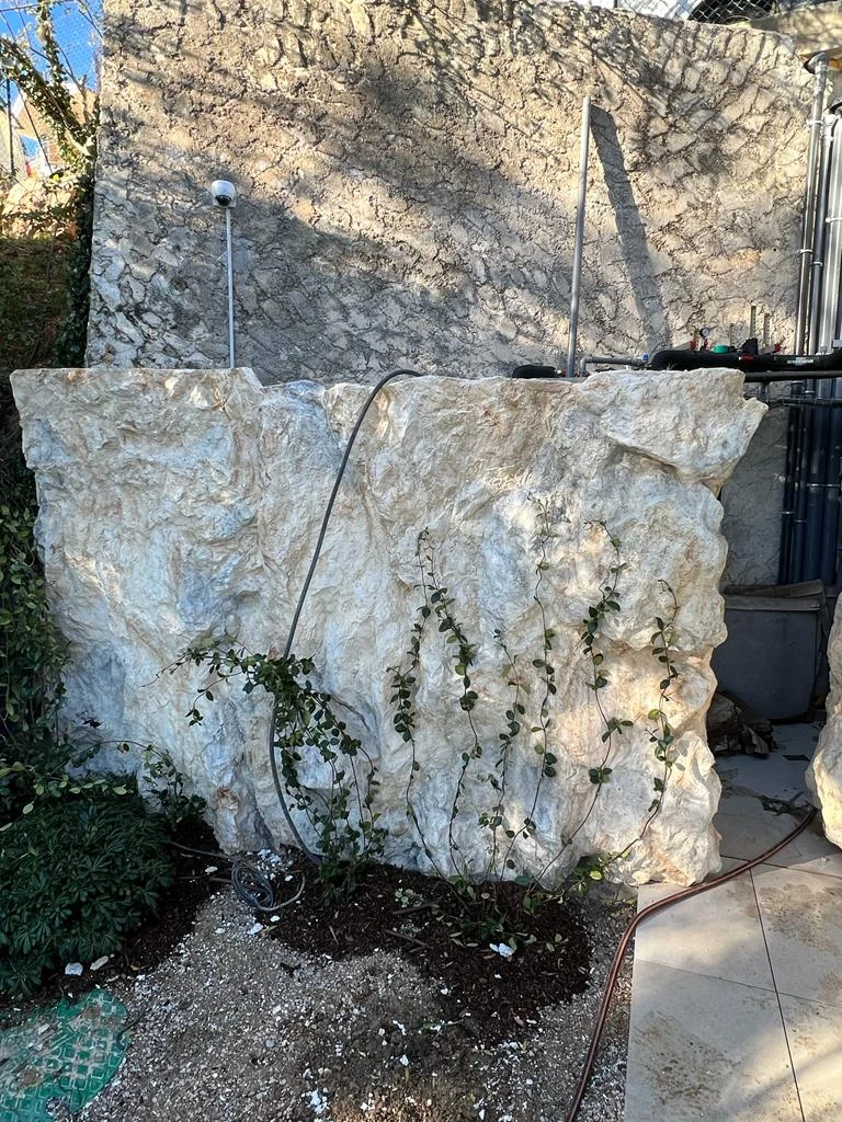 Cache technique en faux rochers avec végétation